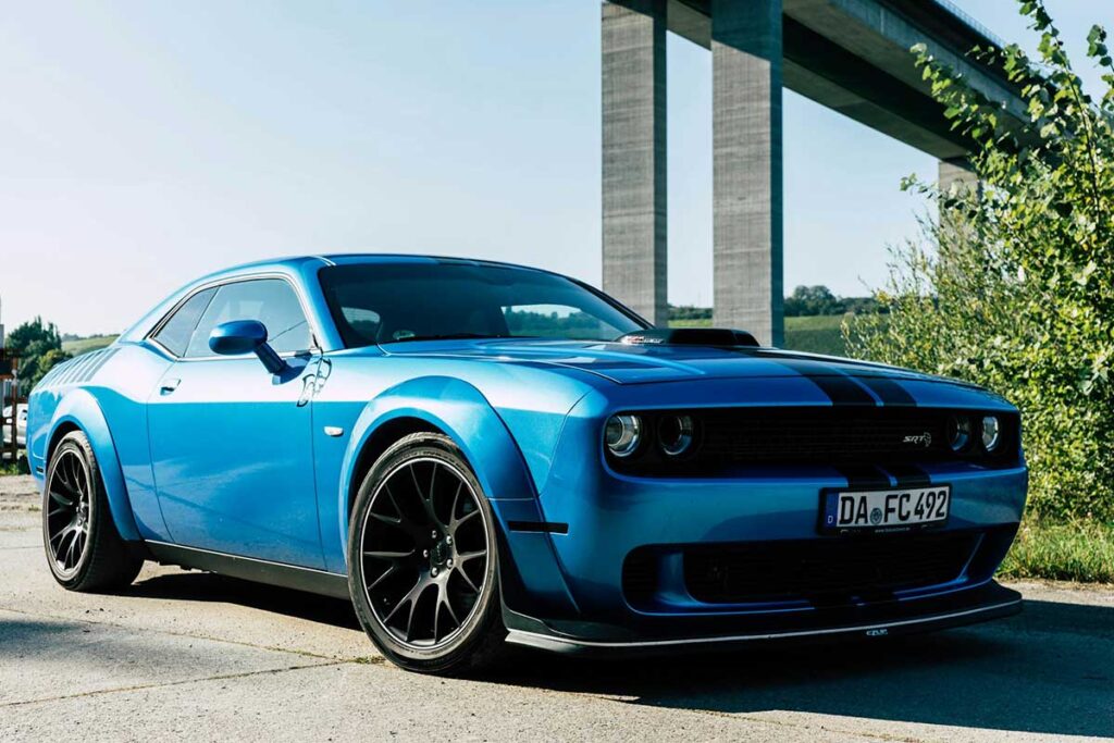 blue-dodge-challenger-parked-on-road-side A blue Dodge Challenger parked on the side of a road, showcasing its sleek design and vibrant color.
