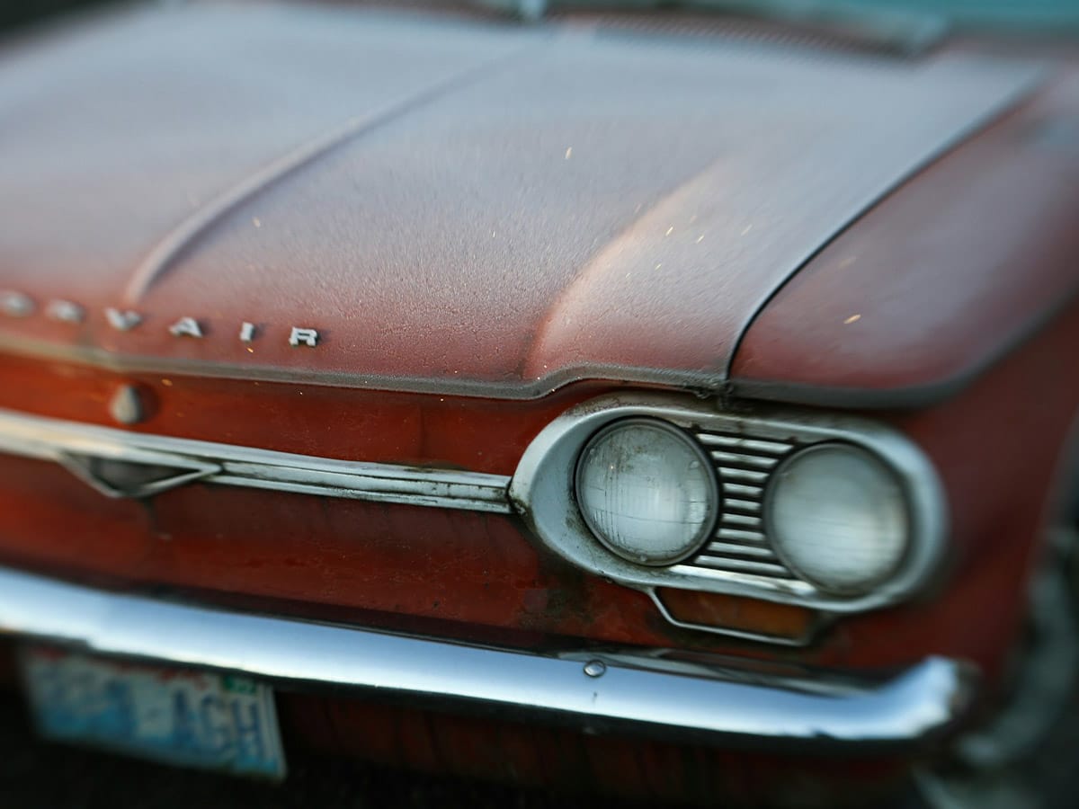 Close-up of an old car showing faded and sun-damaged car paint, highlighting its weathered condition.