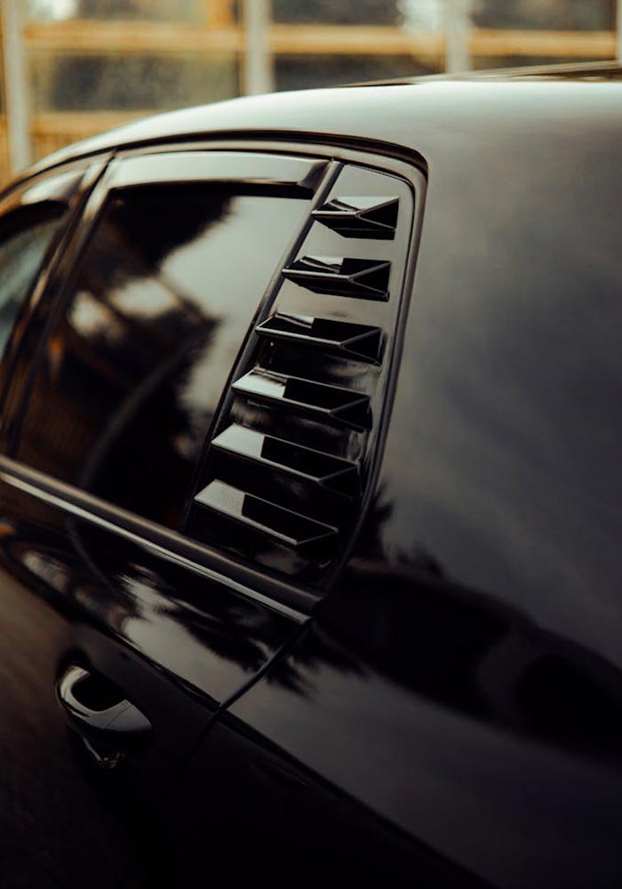 shiny-black-car-with-tinted-windows A black shiny car featuring a tainted window, showcasing clean car's aesthetics.