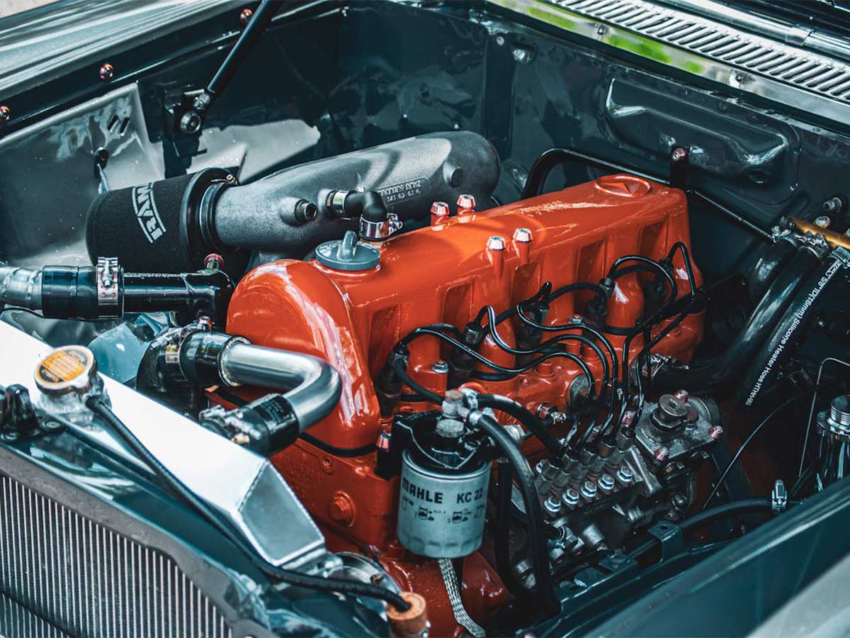 An orange and black engine in a classic car, showcasing visible spark plugs and vintage automotive design elements.