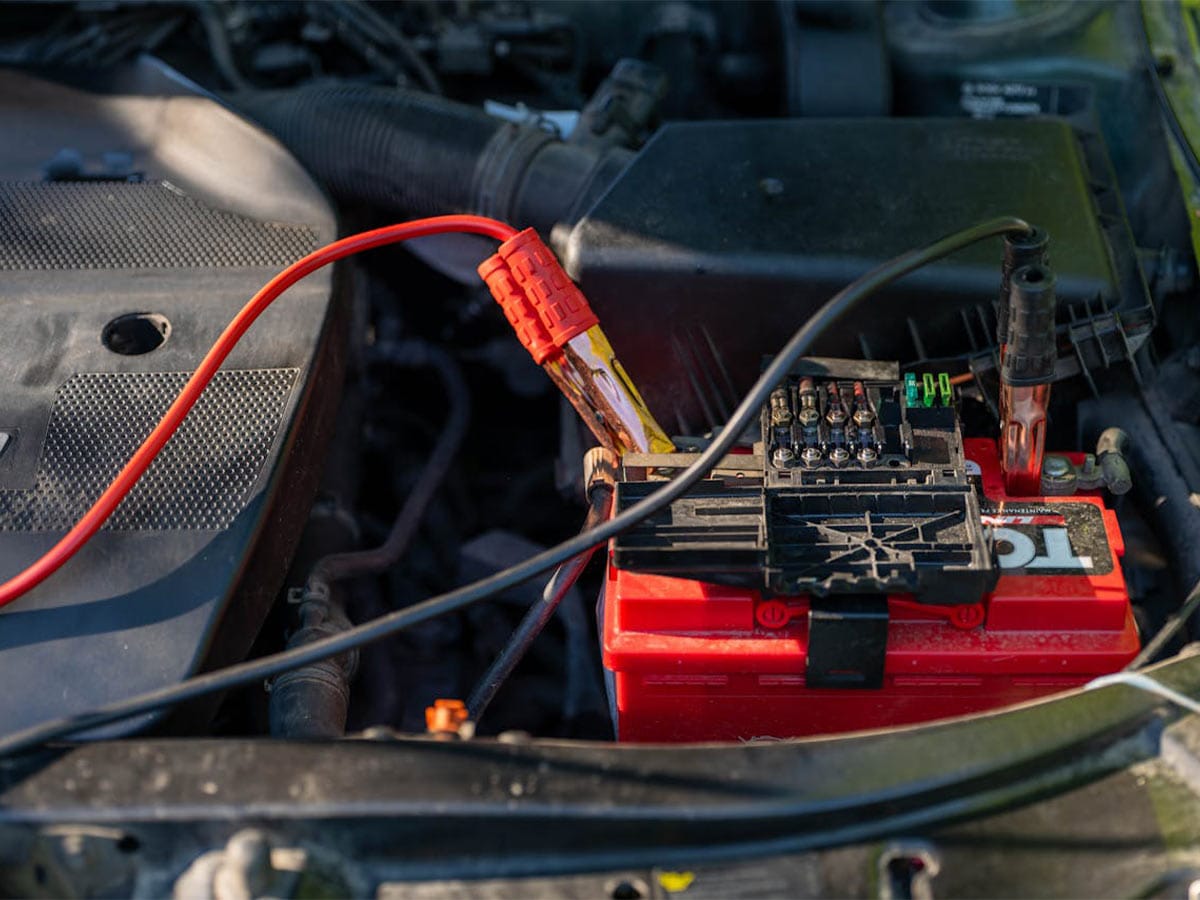 Car battery with a red wire connected, illustrating the impact of leaving lights on auto draining the battery.