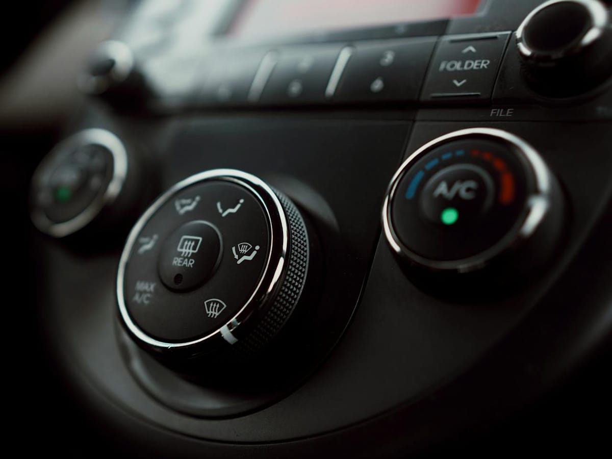 Close-up image of a car dashboard, showcasing electric AC controls and various operational buttons for temperature settings.